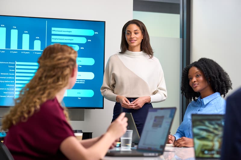 Three women talking and looking at screens