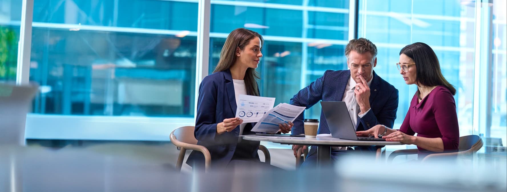 three people looking at laptop at table