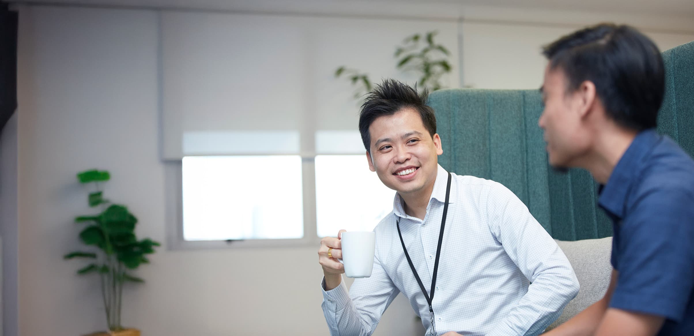 employee smiling and holding coffee cup and talking to another employee